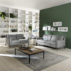 A contemporary living room featuring two C009 QUITETE Sofas in gray, a wooden coffee table, shelves adorned with books and décor, a green accent wall decorated with framed pictures, and a small side table.