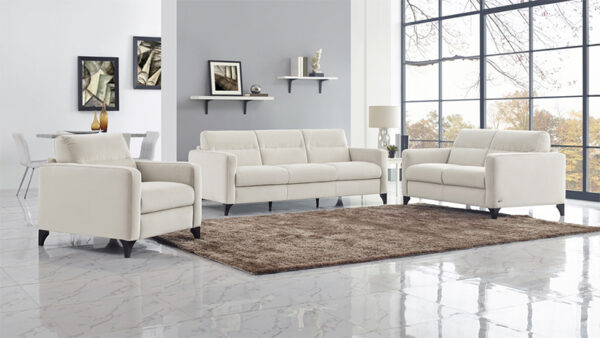 A contemporary living room showcases the C008 FASCINO Living Room Set, including a beige sofa and matching armchair, complemented by a brown rug and wall-mounted shelves adorned with decor. Large windows frame a stunning autumn landscape outside.
